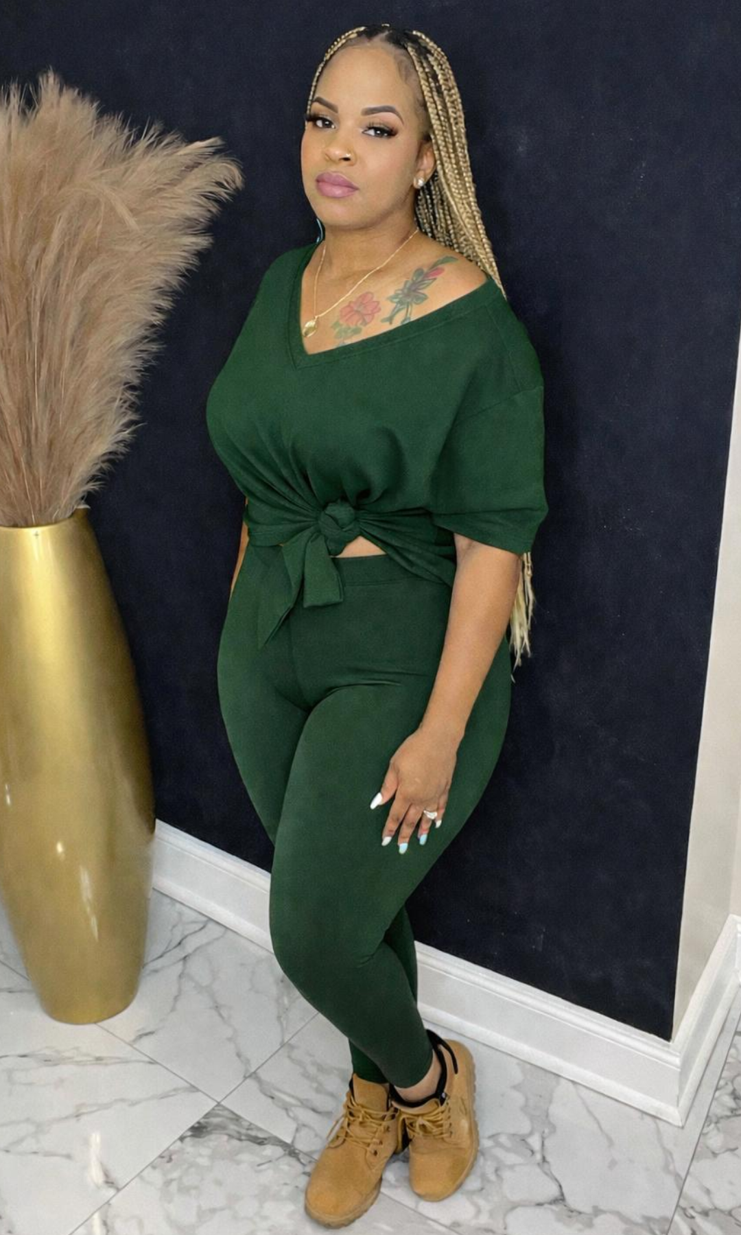 Model wearing Basic Set Dark Green in size medium, front view styled with boots, featuring high-waisted leggings and knotted top detail.