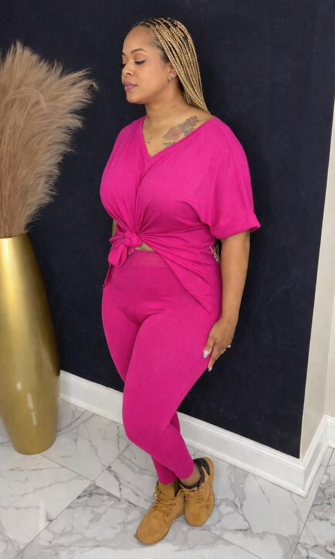 Model wearing Basic Set Fuchsia in size medium, side view styled with boots, featuring high-waisted leggings and knotted top detail.