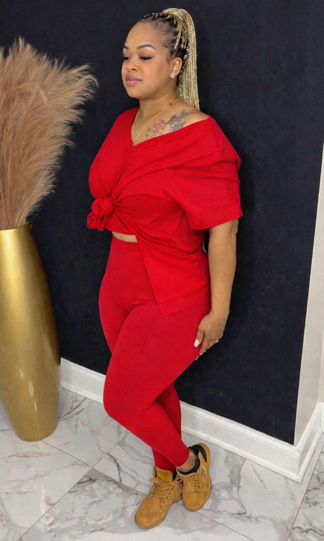 Model wearing Basic Set Ruby in size medium, side view styled with boots, featuring high-waisted leggings and knotted top detail.