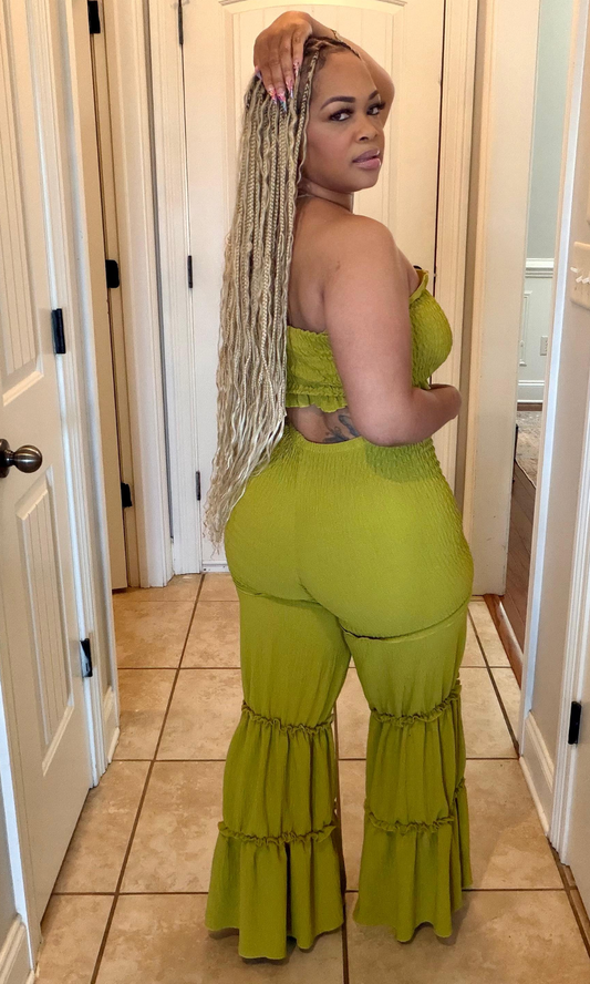 Woman wearing a green outfit with ruffled pants in a home setting