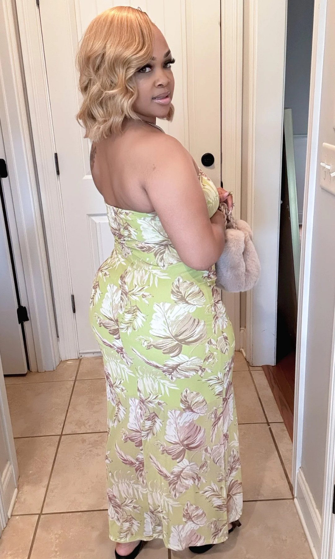 Woman wearing a green floral dress in a room with white walls and tiled floor. Classic Classy Summer Dress