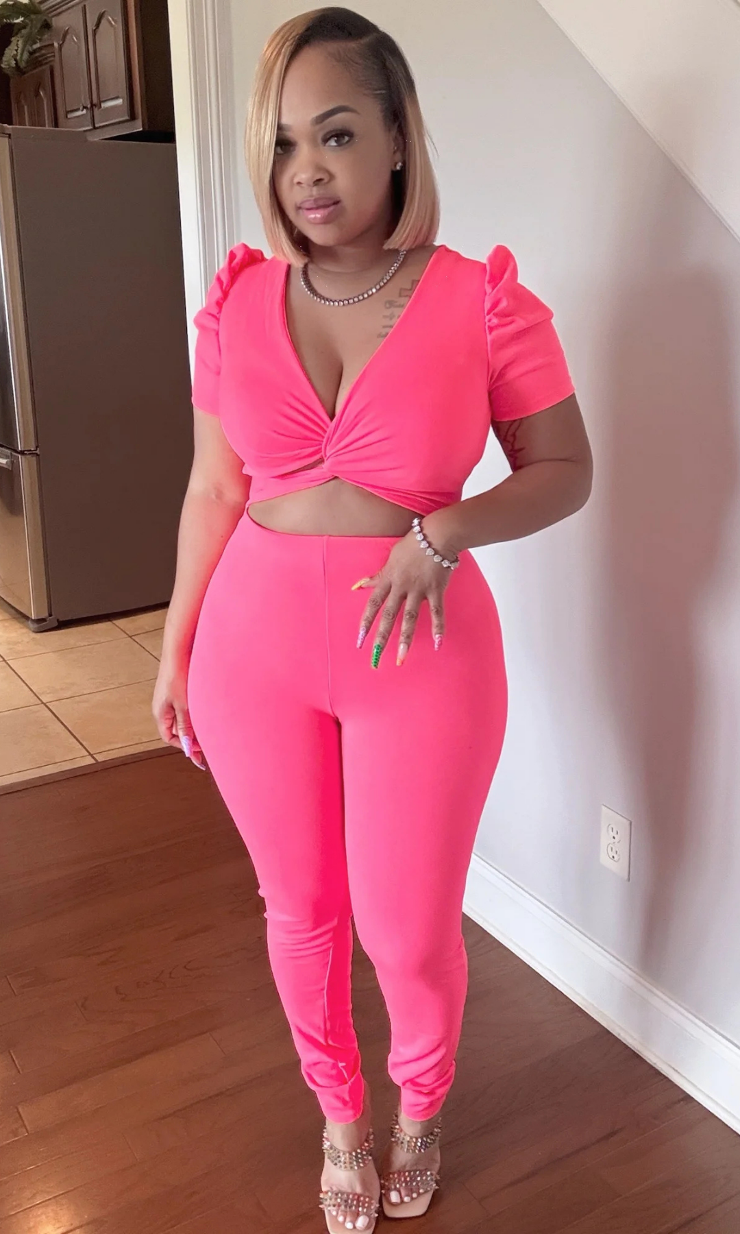 Woman posing in hot pink cut-out jumpsuit with puff sleeves, front view.