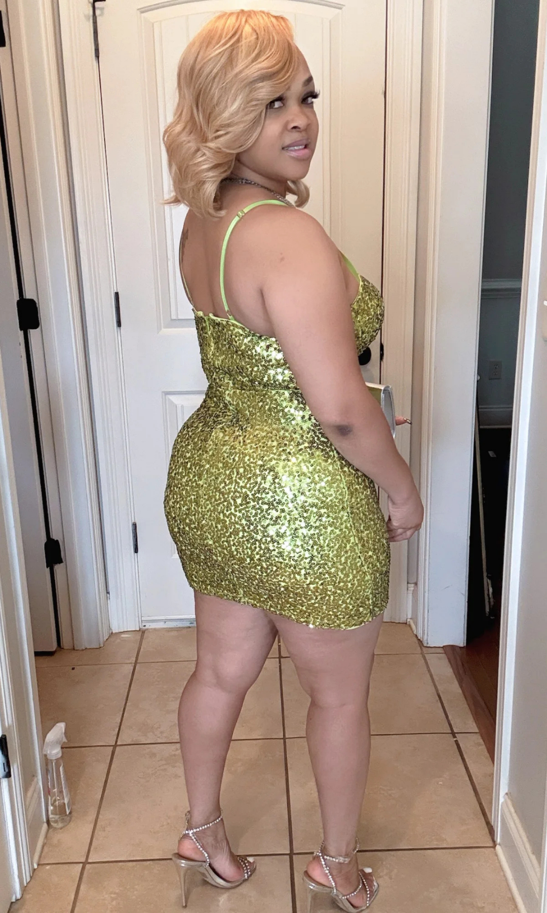 Woman wearing a gold sequin dress standing in a room with a white door.
