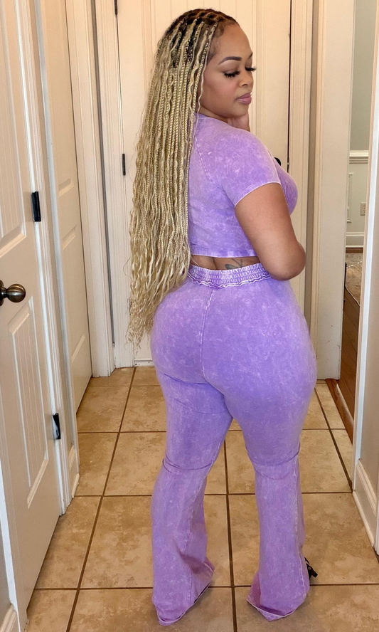 Person wearing a purple outfit standing in a room with tiled floor and white walls.