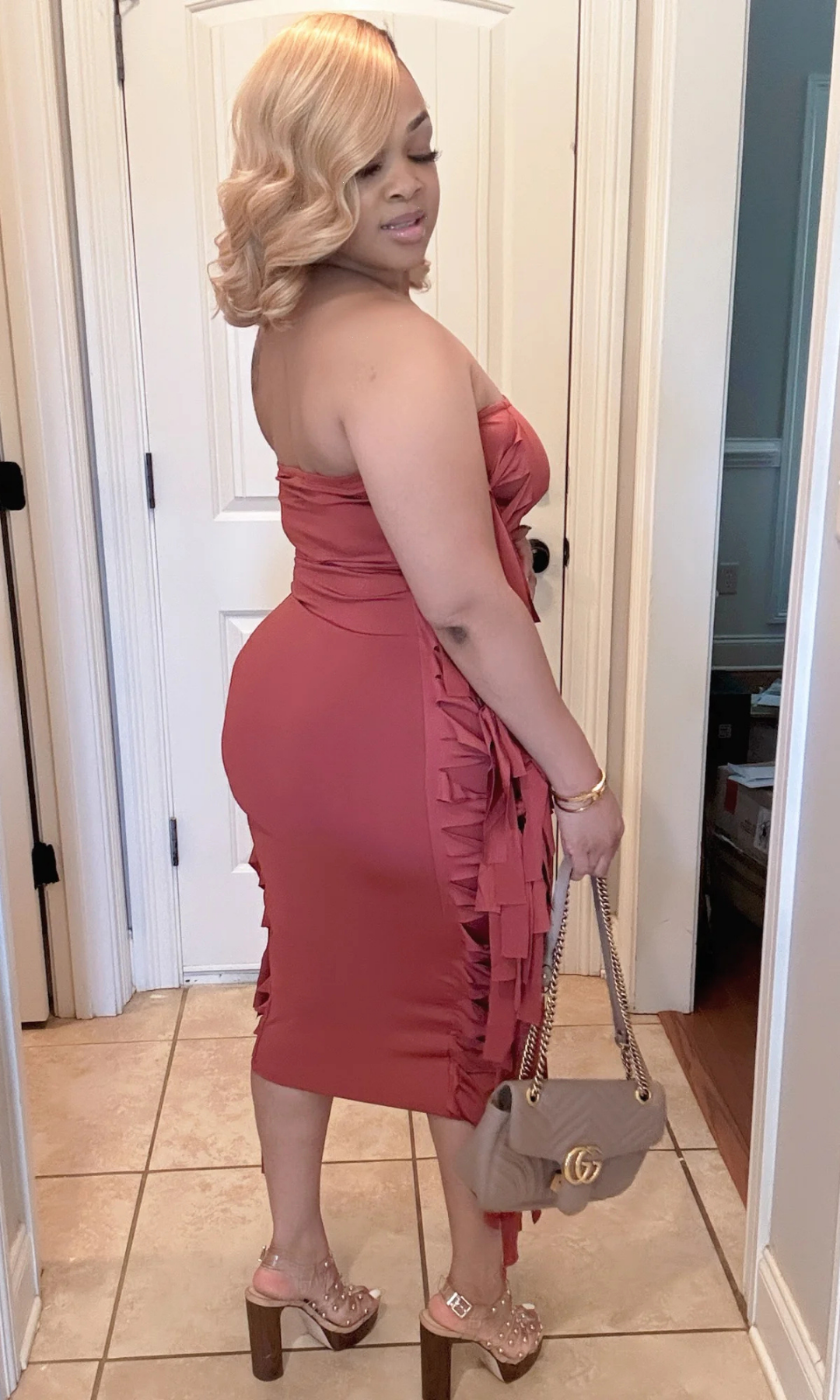 Side view of rust-colored strapless fringe midi dress with heels