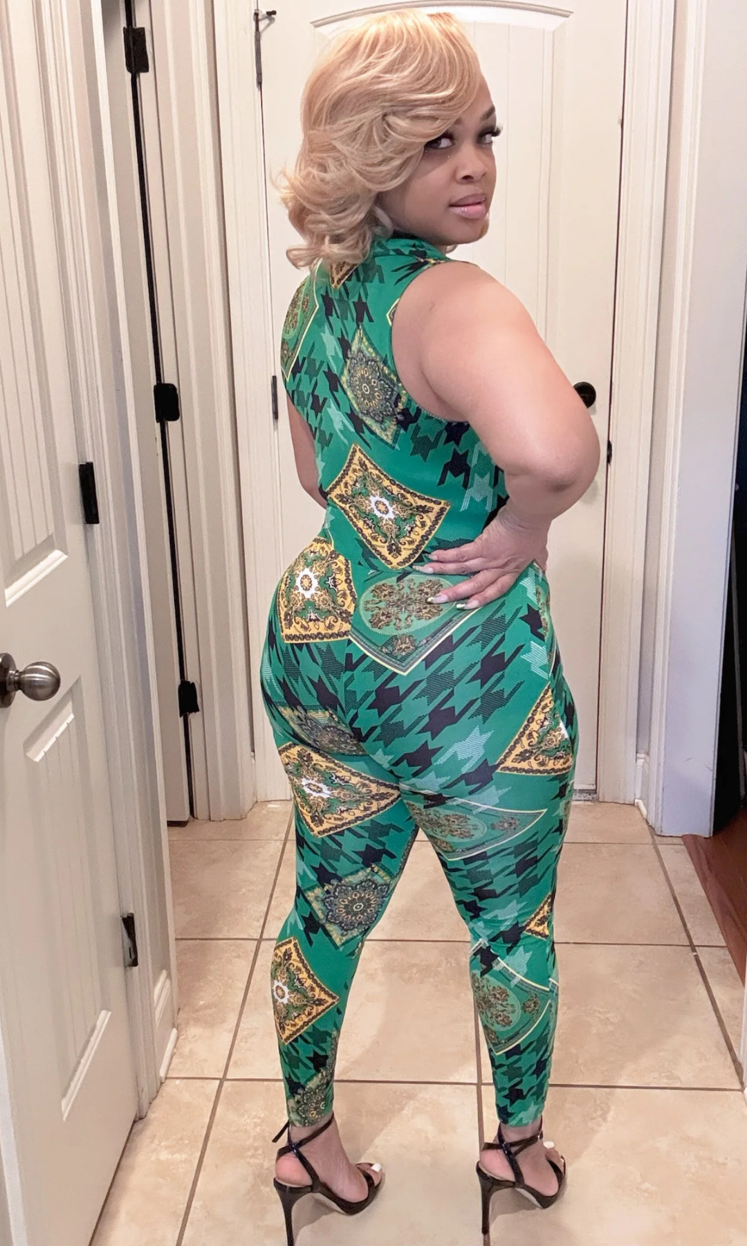 Back Angled Side view of woman in patterned green and gold jumpsuit and heels