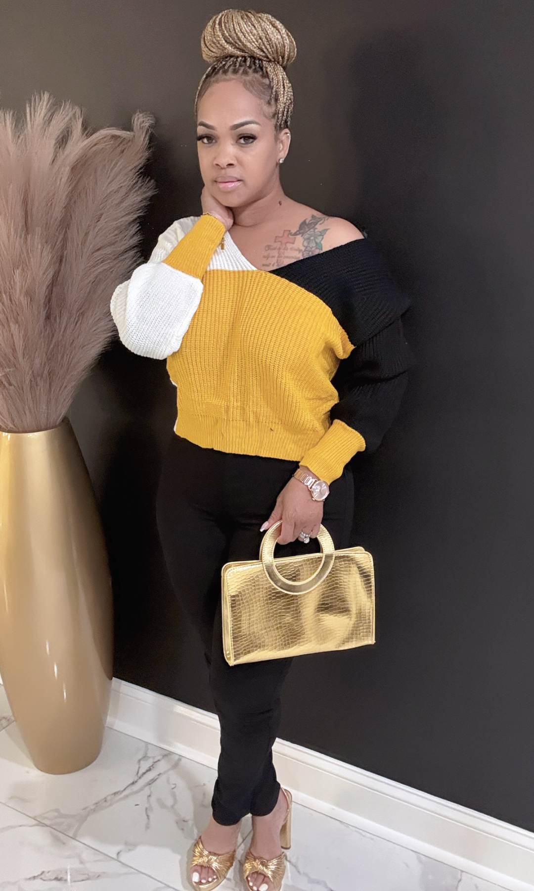 Side view of Yellow Fallover sweater styled with black pants and gold handbag.