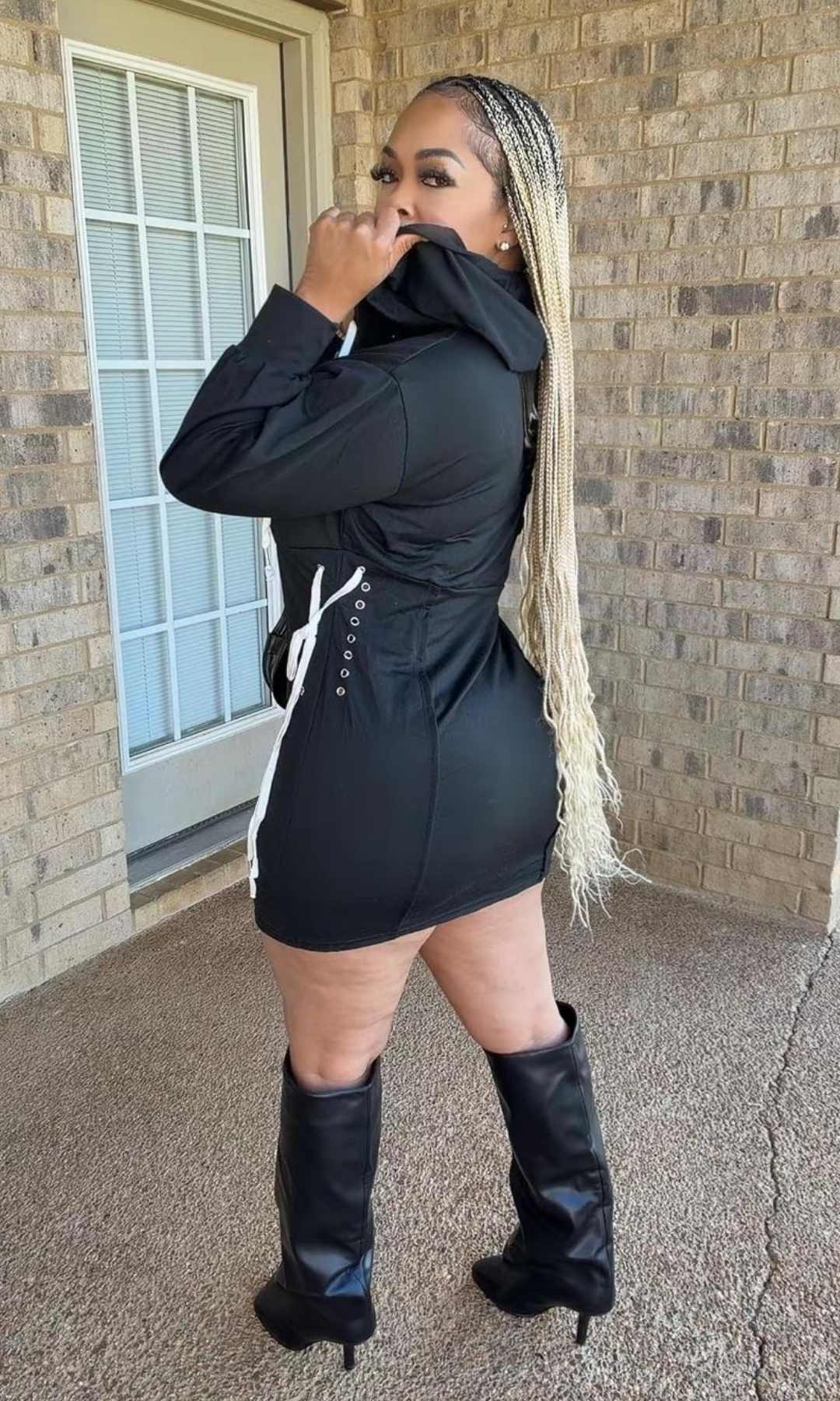 Side and rear view of the Bow Tie Hoodie Dress Black highlighting the adjustable white lace-up bow detailing, metal eyelets, cinched waist, and fitted mini-length design.