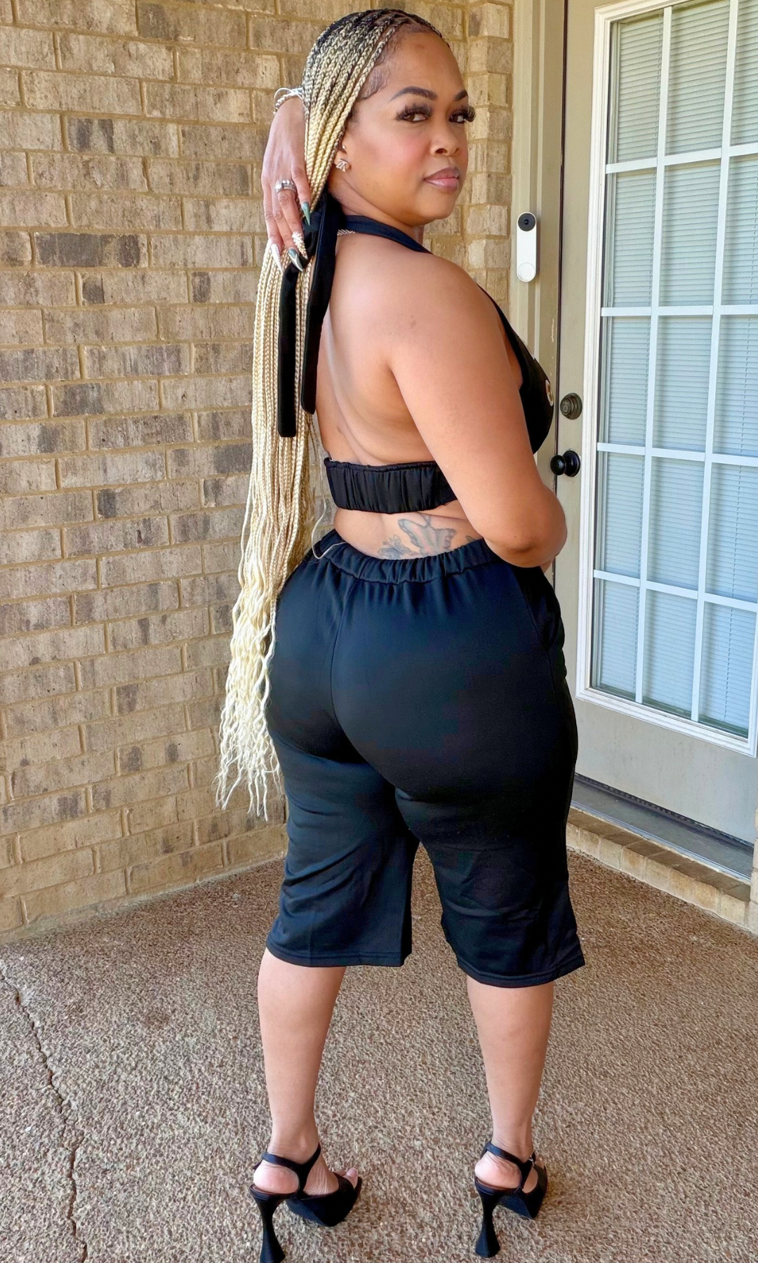 Back and side view of the black Wrestler Set showing the open-back halter crop top, elastic waistband, and matching knee-length shorts.