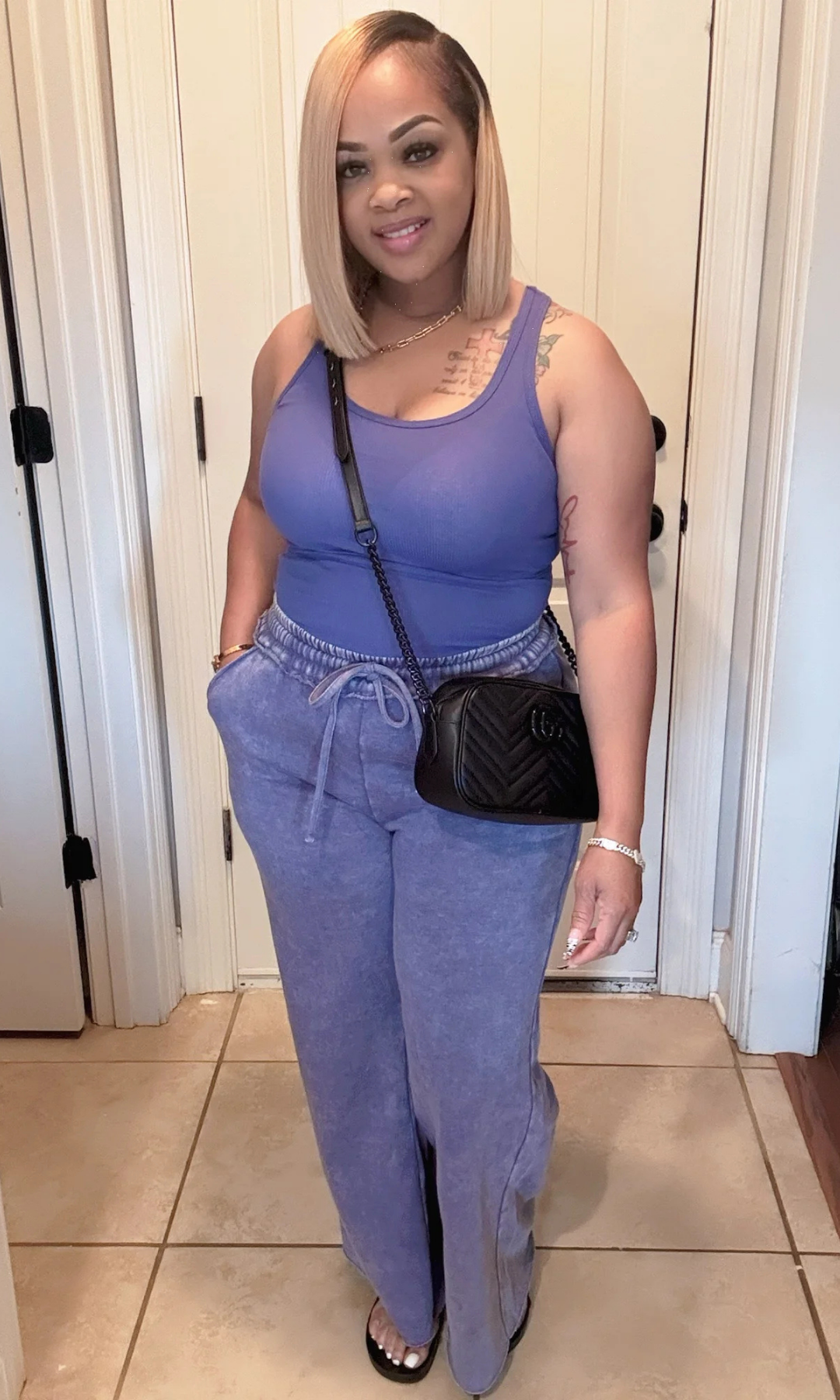 Side view of model wearing washed blue tank and wide-leg pants with black crossbody bag.