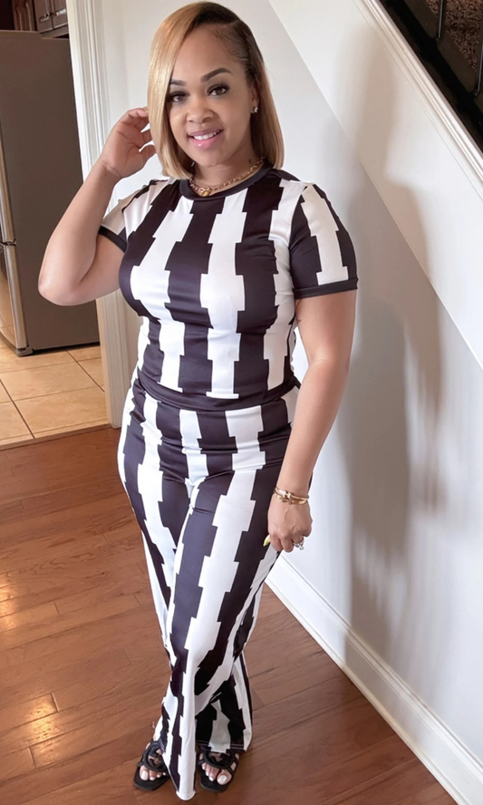 Woman wearing Aztec Black 2-piece set with black-and-white geometric print, short-sleeve fitted top, and flared pants, front view.