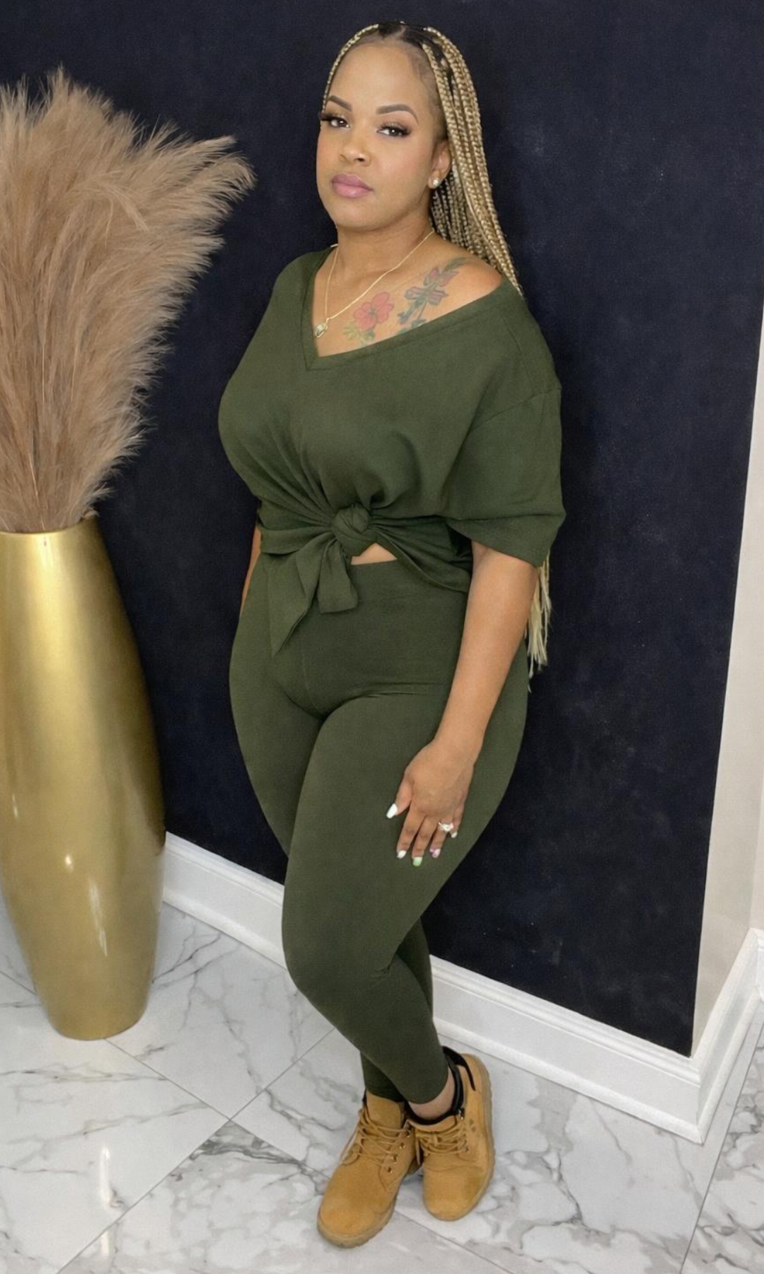 Model wearing Basic Set Dark Olive in size medium, front view styled with boots, featuring high-waisted leggings and knotted top detail.
