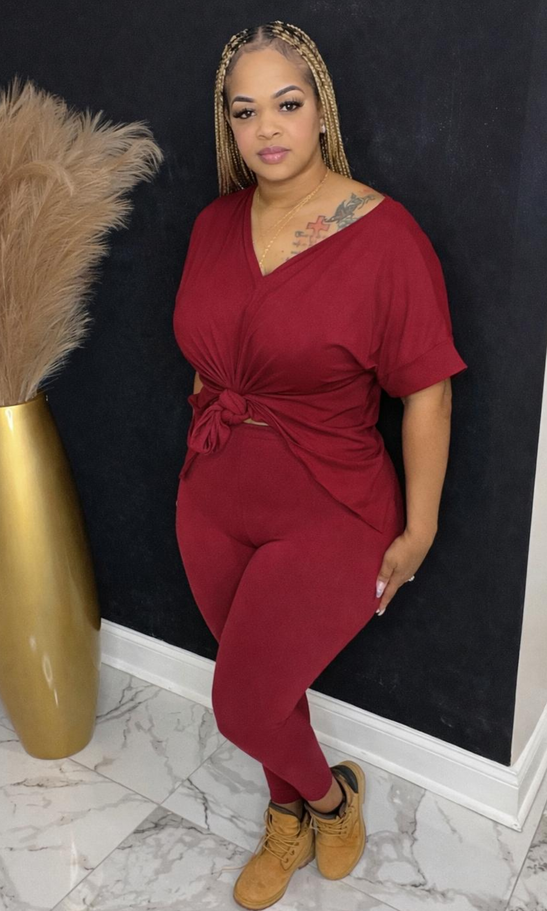 Model wearing Basic Set Cabernet in size medium, front view styled with boots, featuring high-waisted leggings and knotted top detail.