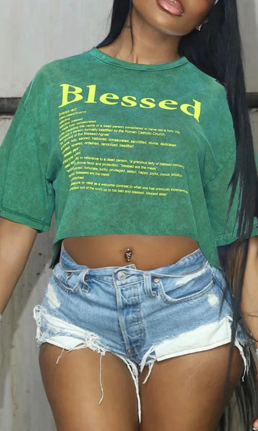 Person wearing a green 'Blessed' t-shirt and denim shorts.