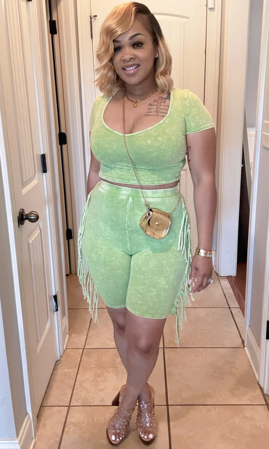 Woman wearing green two-piece fringe set, front view, styled with heels.