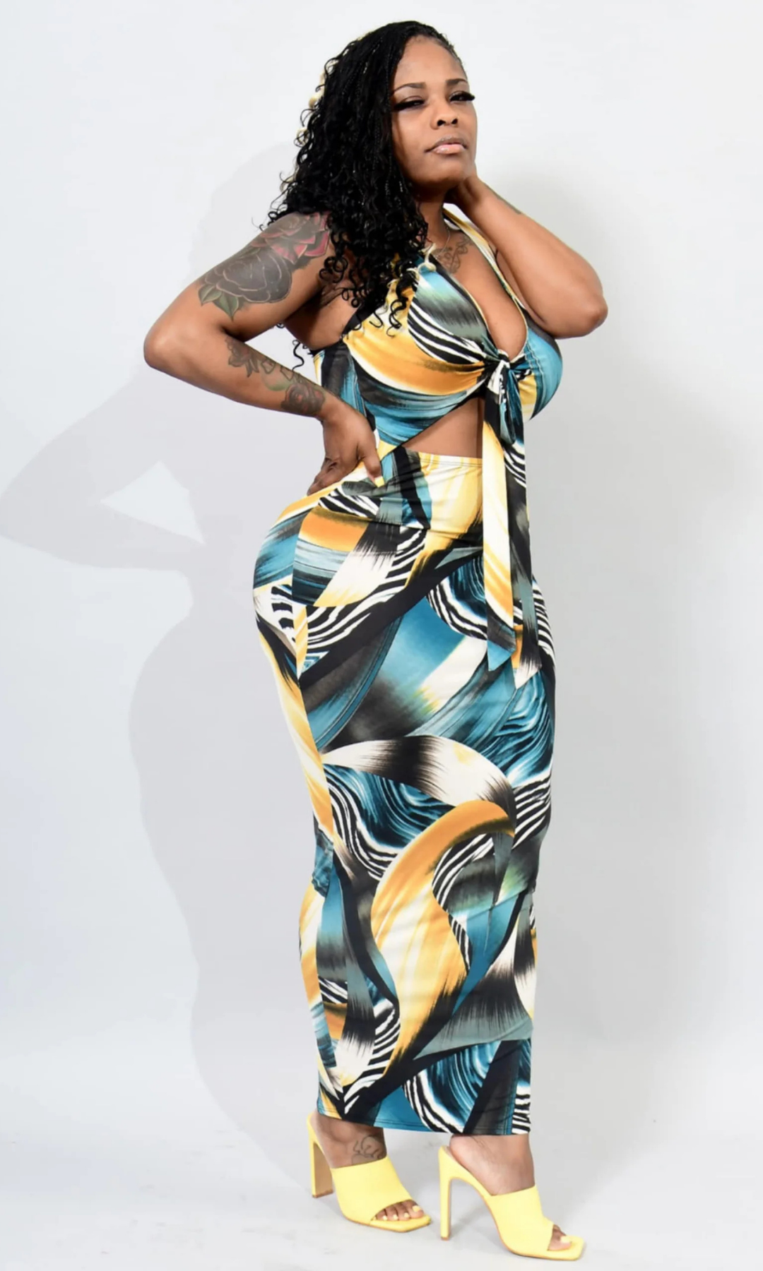 Woman wearing a colorful patterned dress with yellow shoes on a white background