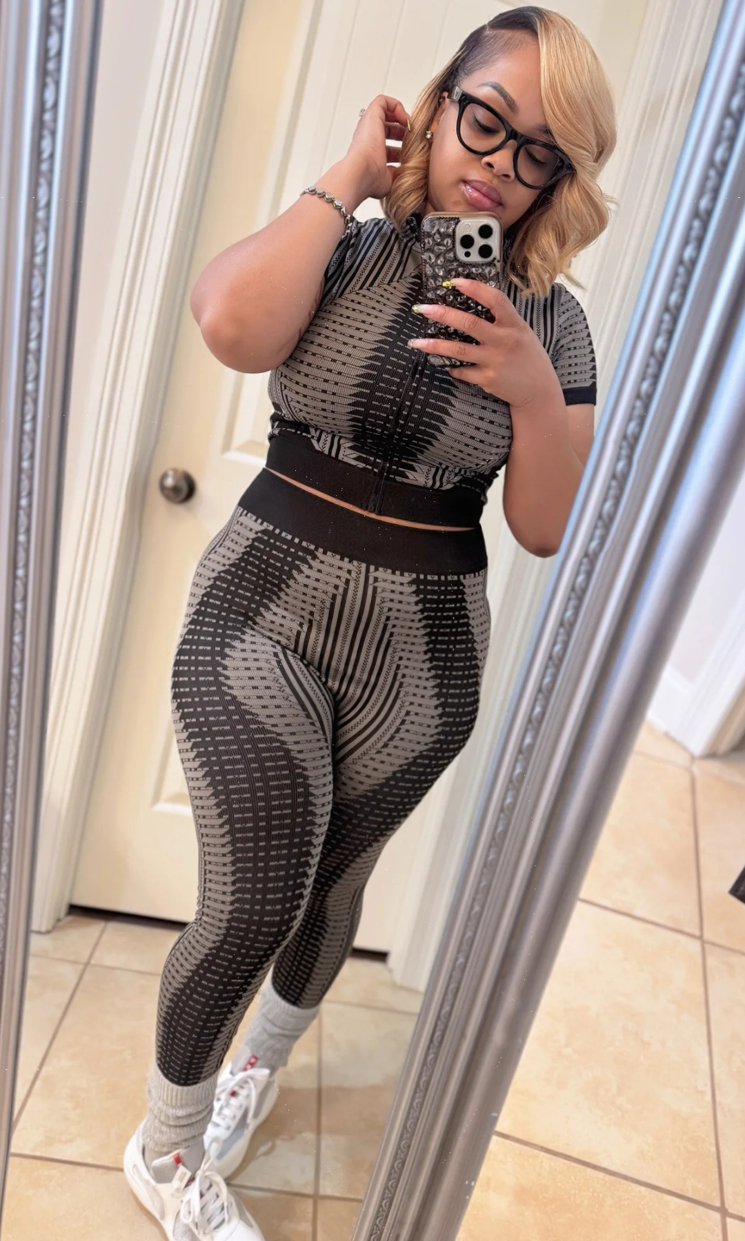 Woman wearing a patterned outfit taking a mirror selfie.