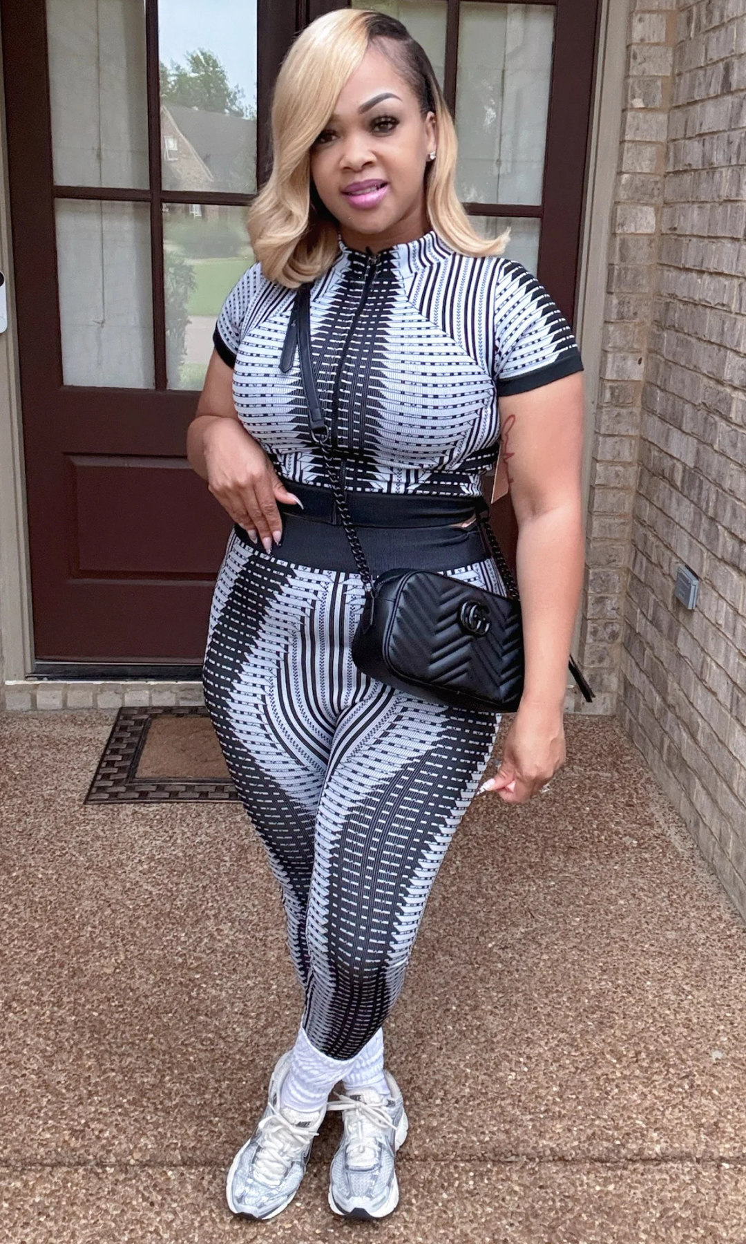 Woman in a patterned outfit standing on a porch