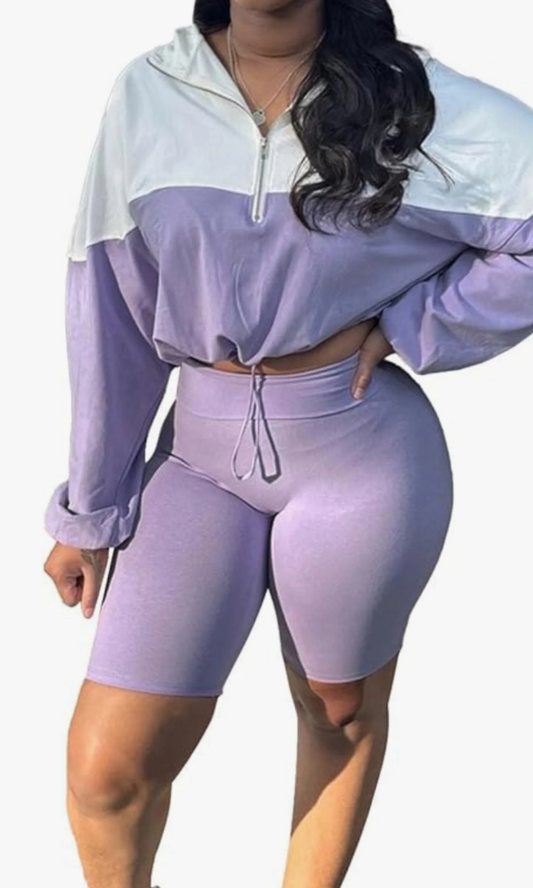 Person wearing a two-piece Color me lavender athletic outfit with a white top and matching shorts on a plain background. 