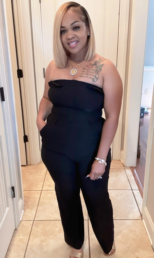 Woman wearing a black Dark Sky strapless jumpsuit indoors.