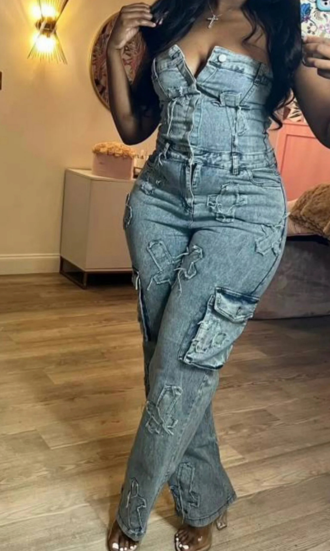 Person wearing a denim, Don't Cross Me one-piece outfit with patches in a room.