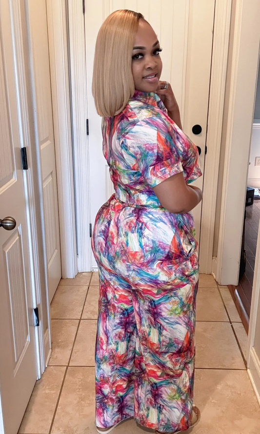 Woman wearing a colorful patterned dress standing in a doorway.