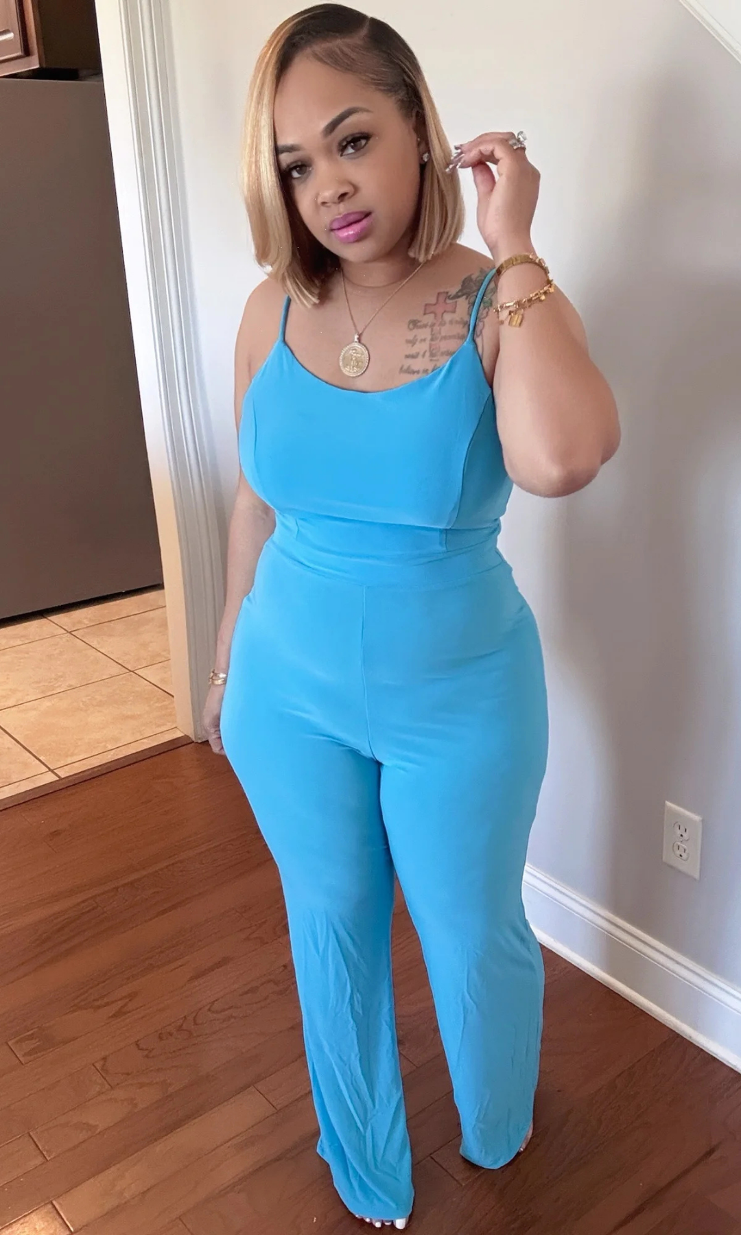 Front view of model wearing vibrant blue jumpsuit with spaghetti straps and straight-leg pants indoors.