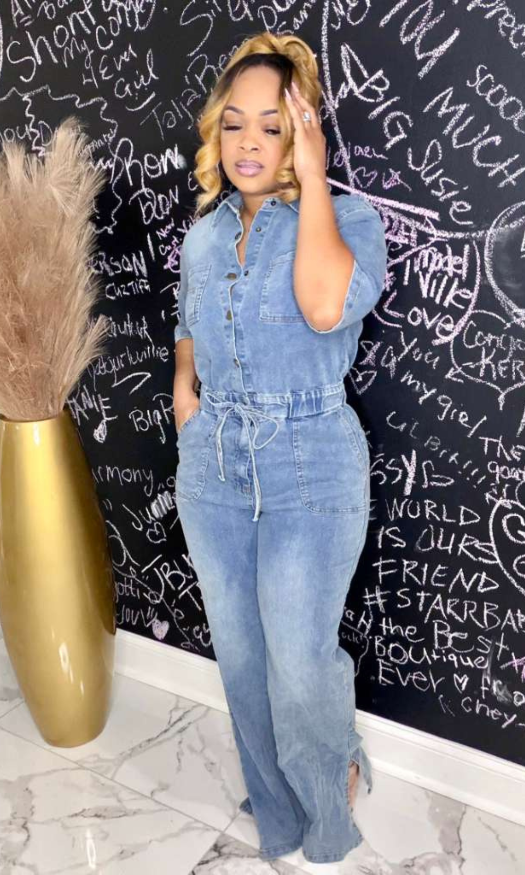 Lex Jean Romper front view – Model wearing a medium, button-front denim romper with cinched waist and short sleeves