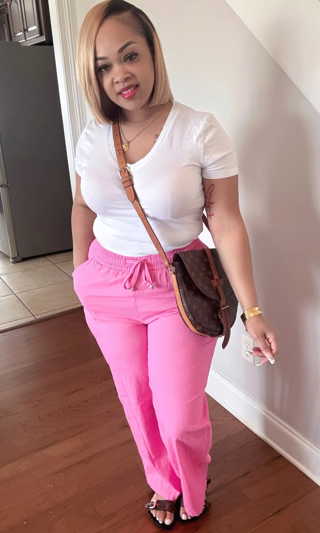 Woman wearing Linen Pink pants with white top, front view.