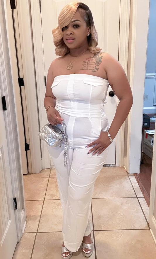 Woman wearing Moon Tube Jumpsuit — strapless white wide-leg jumpsuit with silver handbag.