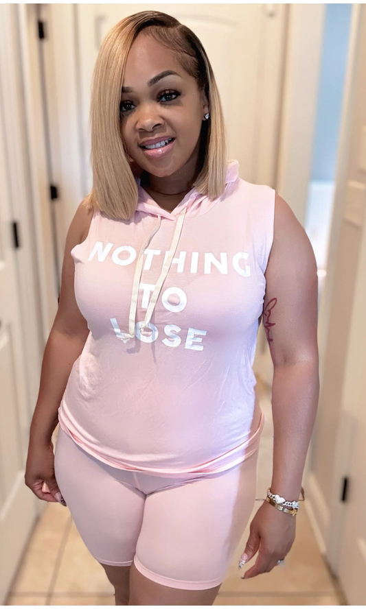 Woman wearing light pink biker shorts and hooded sleeveless top with “Nothing To Lose” text.