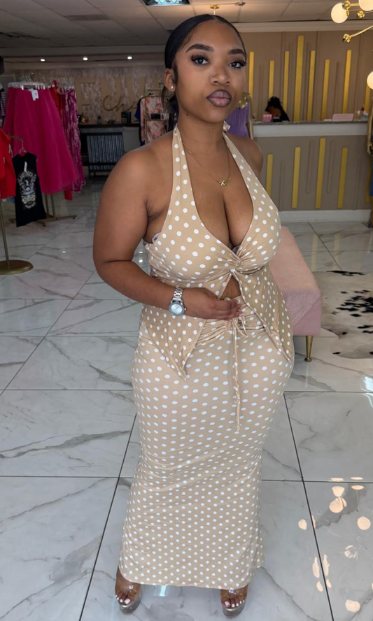 Woman wearing the Nude Polka halter maxi dress featuring a front twist detail, waist cutout, and white polka dot print.
