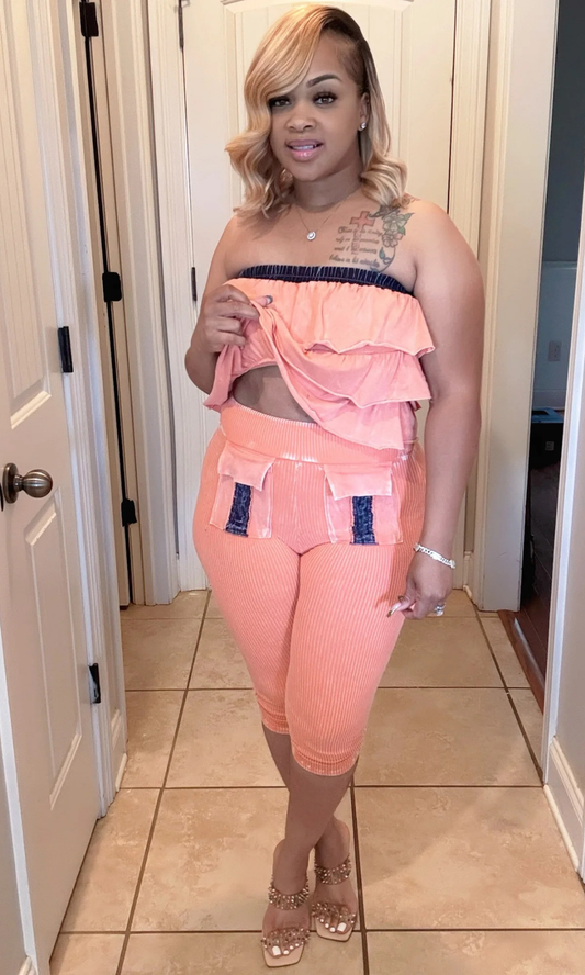 Woman wearing Orange Mania two-piece set with strapless ruffle top and cropped leggings.