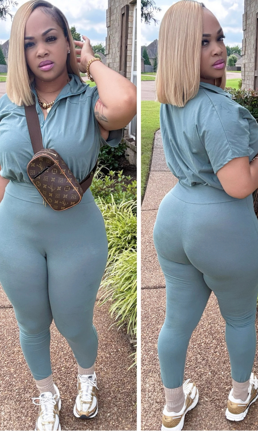 Woman wearing a teal jumpsuit with a brown bag, standing outdoors.