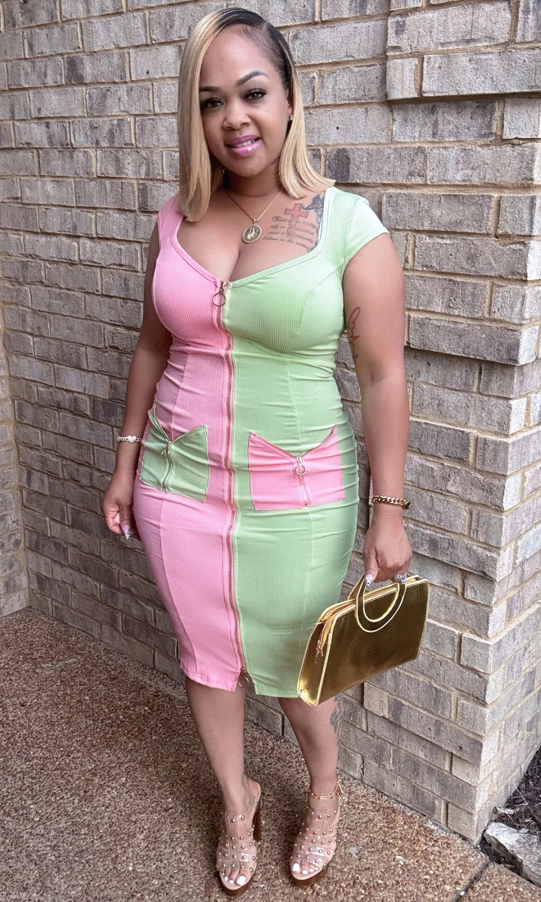 Front angled view of pink and green two-tone dress with gold handbag