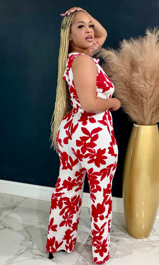 Woman wearing the Red Garden Jumpsuit featuring a bold red floral print, sleeveless design, and wide-leg silhouette.