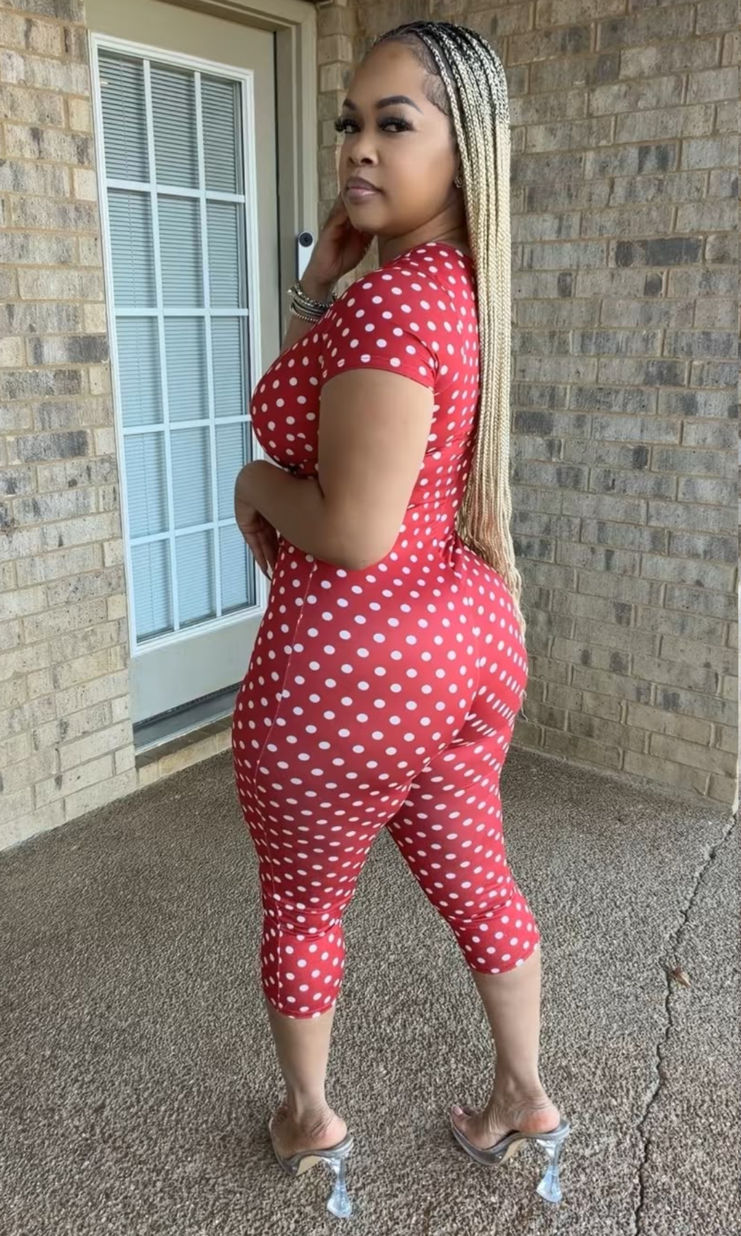 Side and back view of the Red Polka Babe Jumpsuit showing its fitted silhouette, allover white polka dot pattern, short sleeves, and below-the-knee length.