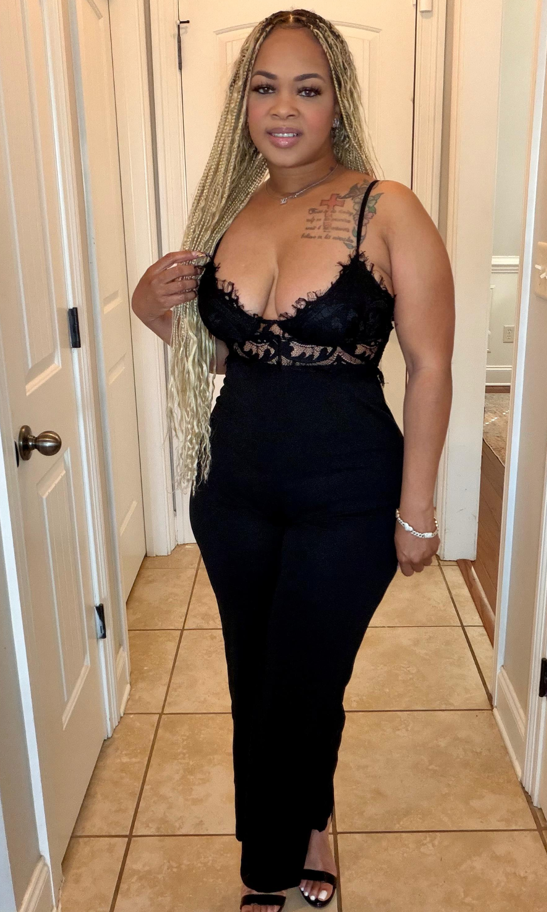Woman wearing a black lace top and black pants in a hallway.