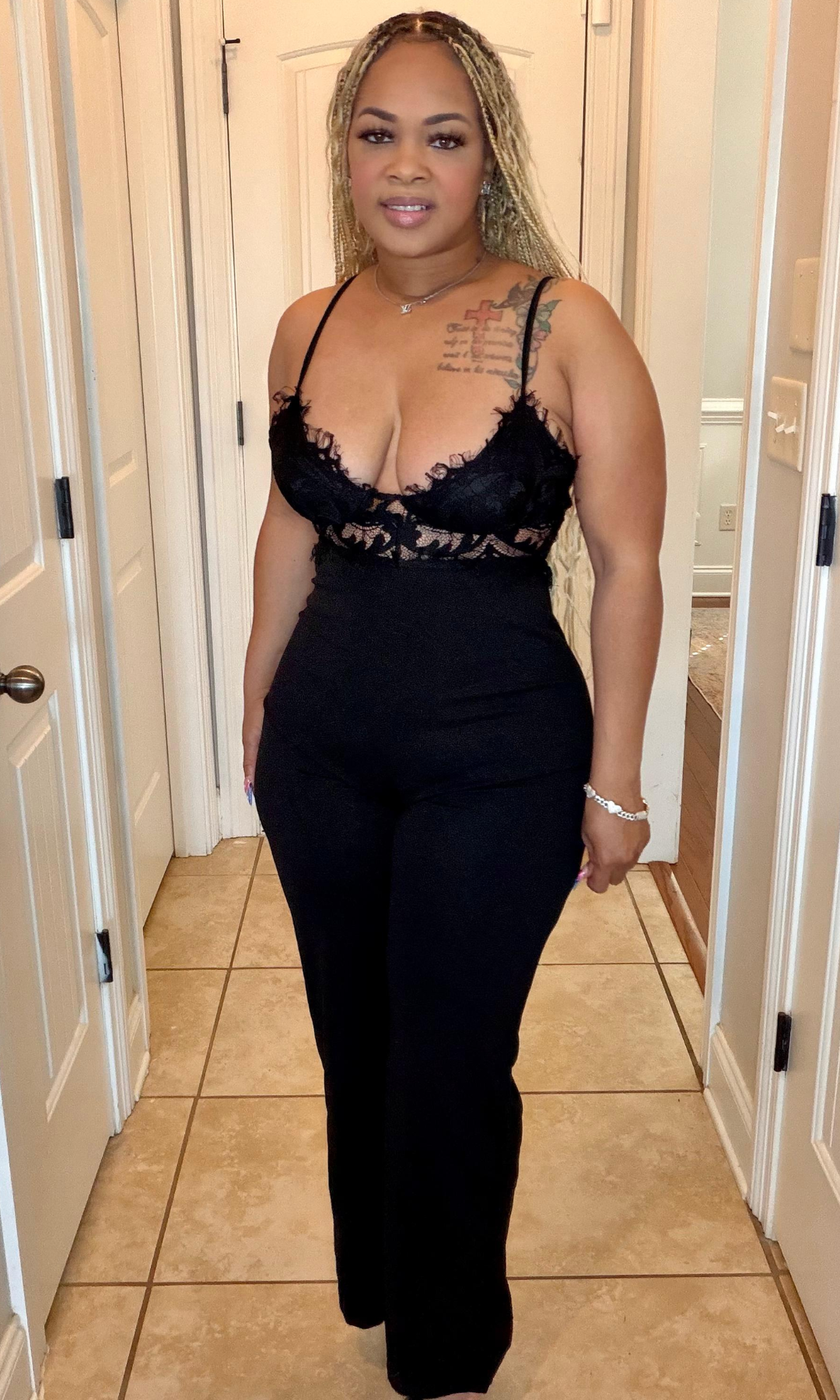 Woman wearing a black lace top and black pants in a hallway.