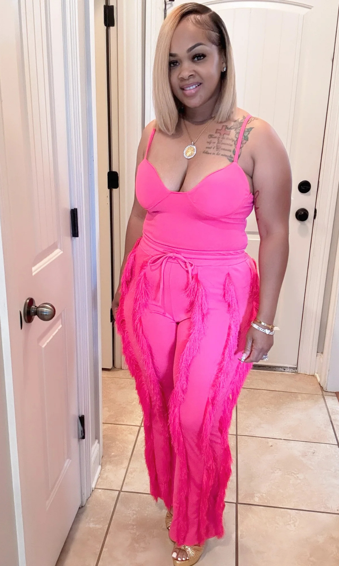 Front view of woman wearing Shimmy Pink 2-piece short set with tassel details.