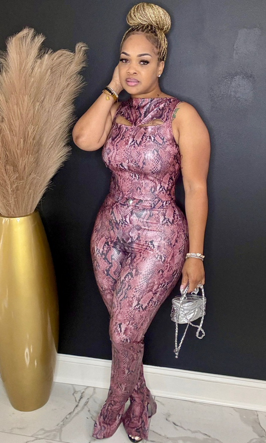 Woman in a pink sequin dress posing against a dark wall with decorative elements.