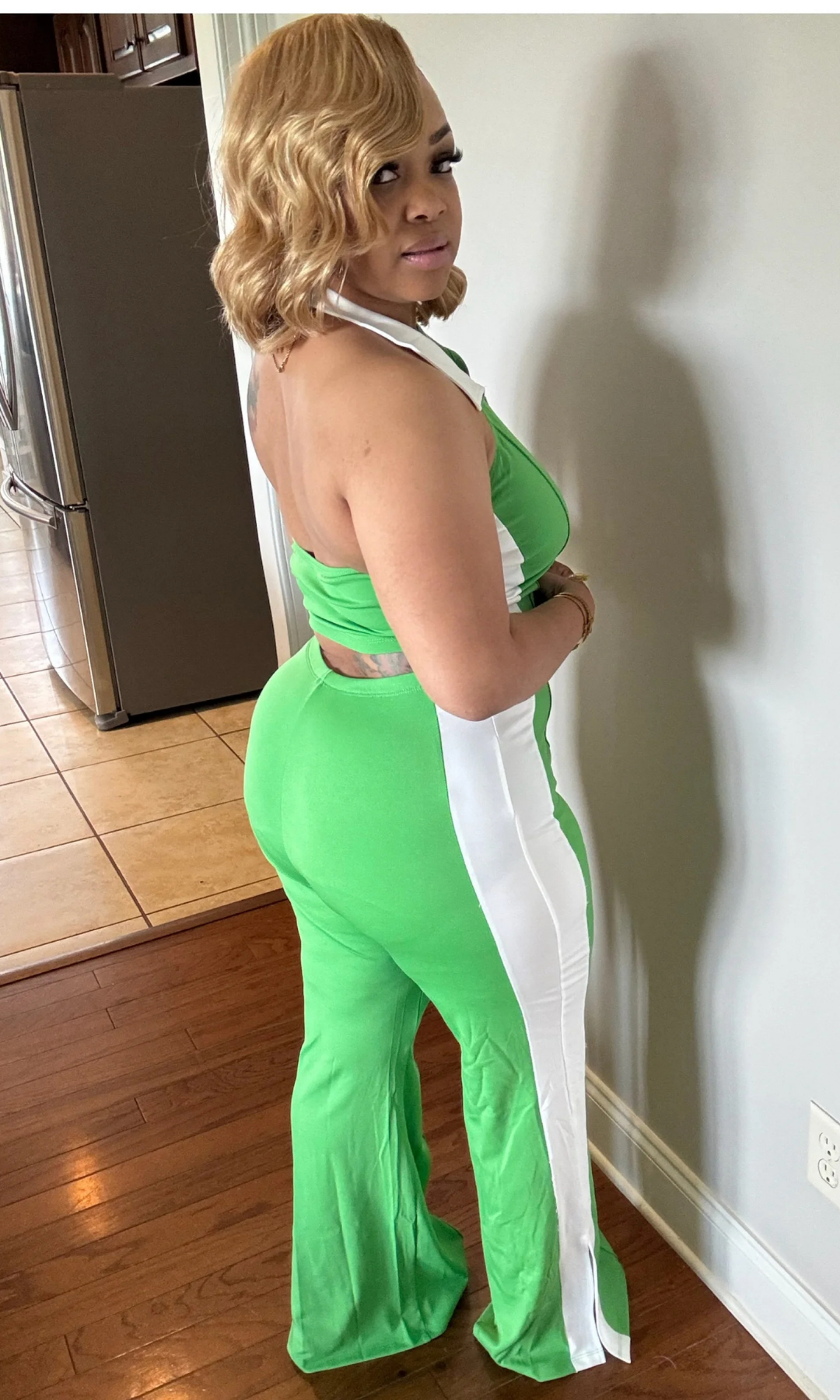 Side-back view of woman wearing the Strike A Pose Green 2-piece set with halter top and split-hem flare pants.