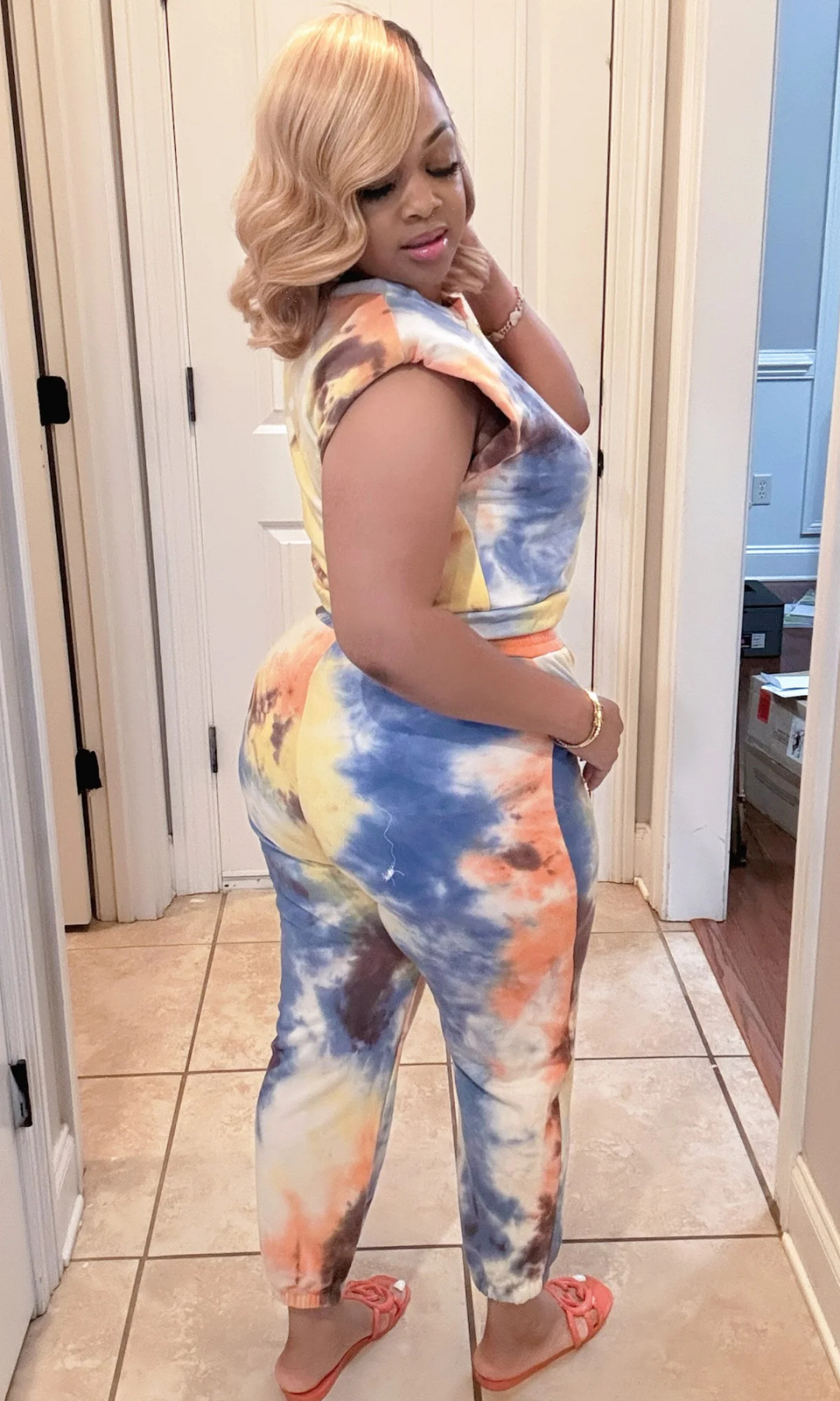 Side-back view of woman wearing the Take It Back Set showing colorful tie-dye joggers and sleeveless padded-shoulder top.