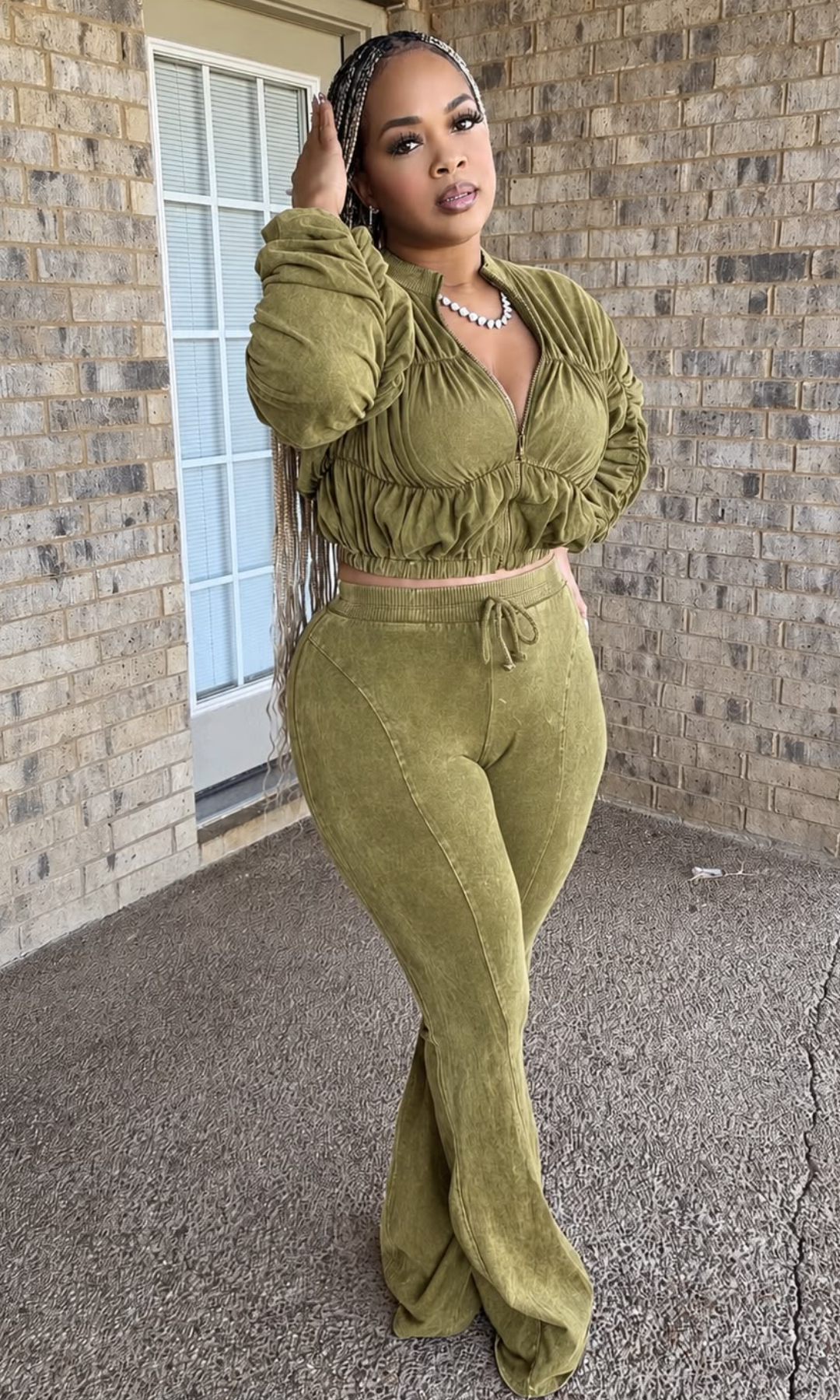 The woman is wearing a live-green acid-wash two-piece matching set featuring a cropped zip-front jacket with ruched detailing, gathered long sleeves, and high-waisted drawstring flared pants displayed on a mannequin.