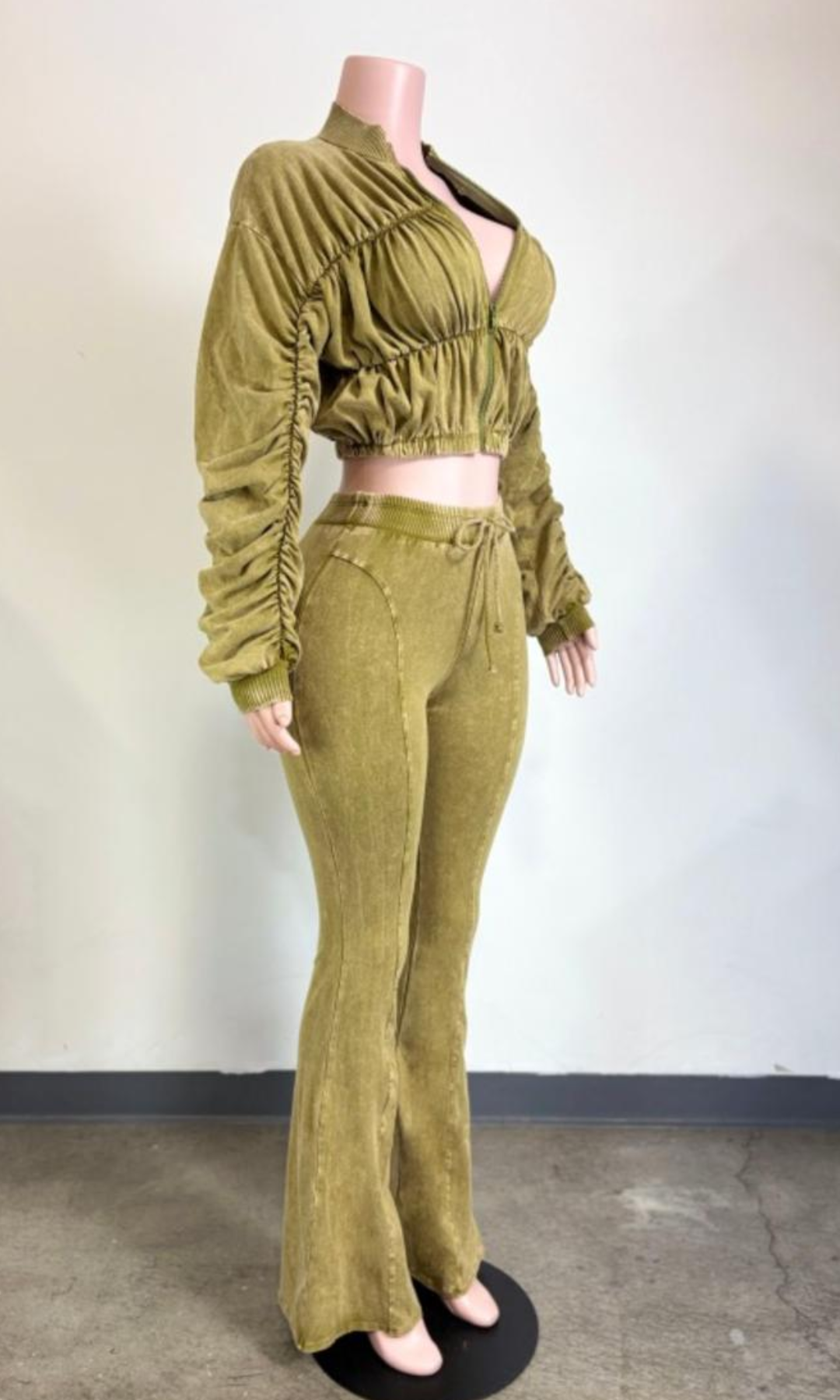 Side view of The Weekend Ruched Set Green showing the cropped ruched jacket, gathered sleeves, fitted high-waisted pants, and flared leg silhouette.