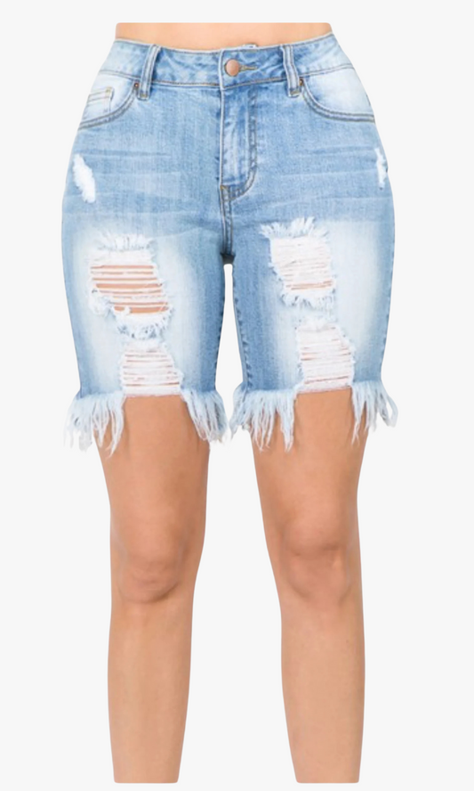 Close-up front view of woman wearing Tight Fit Ripped Shorts in light blue denim with heavy front distressing, frayed hems, and mid-thigh length.