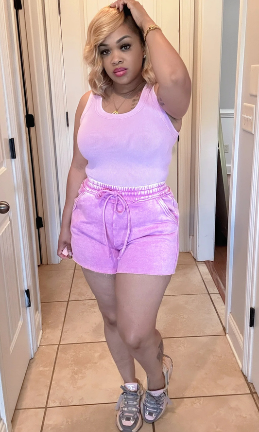 Vibe Set Lilac Front View – Woman wearing a lilac sleeveless ribbed top with matching drawstring shorts, styled with sneakers in a casual indoor setting.

