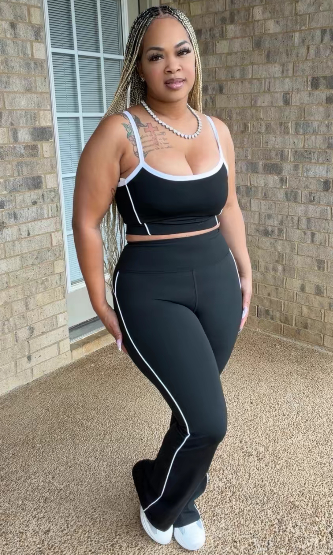 Woman modeling the Blackout Trim Set featuring a black spaghetti-strap crop top with white contrast piping and matching high-waisted, slightly flared pants.