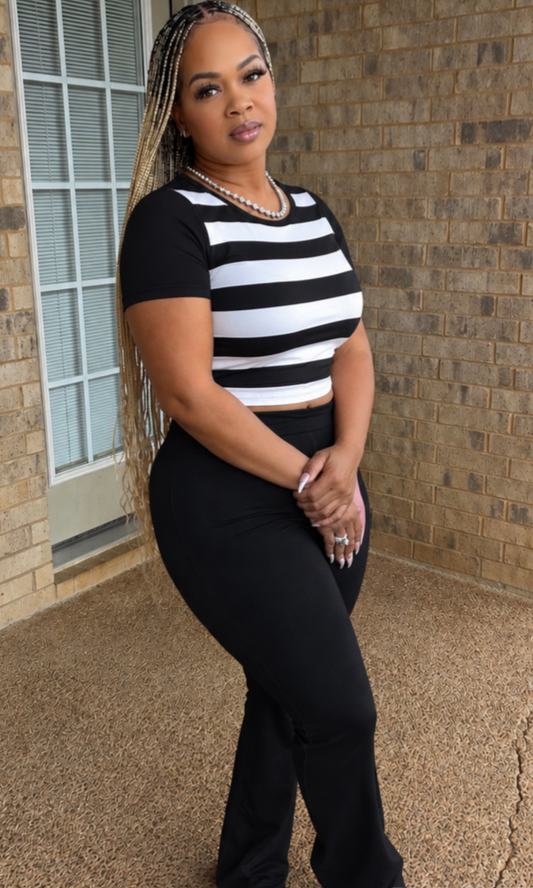 Woman modeling the Cookies & Cream 2pc Set featuring a fitted black-and-white striped short-sleeve crop top and coordinating high-waisted black full-length pants.