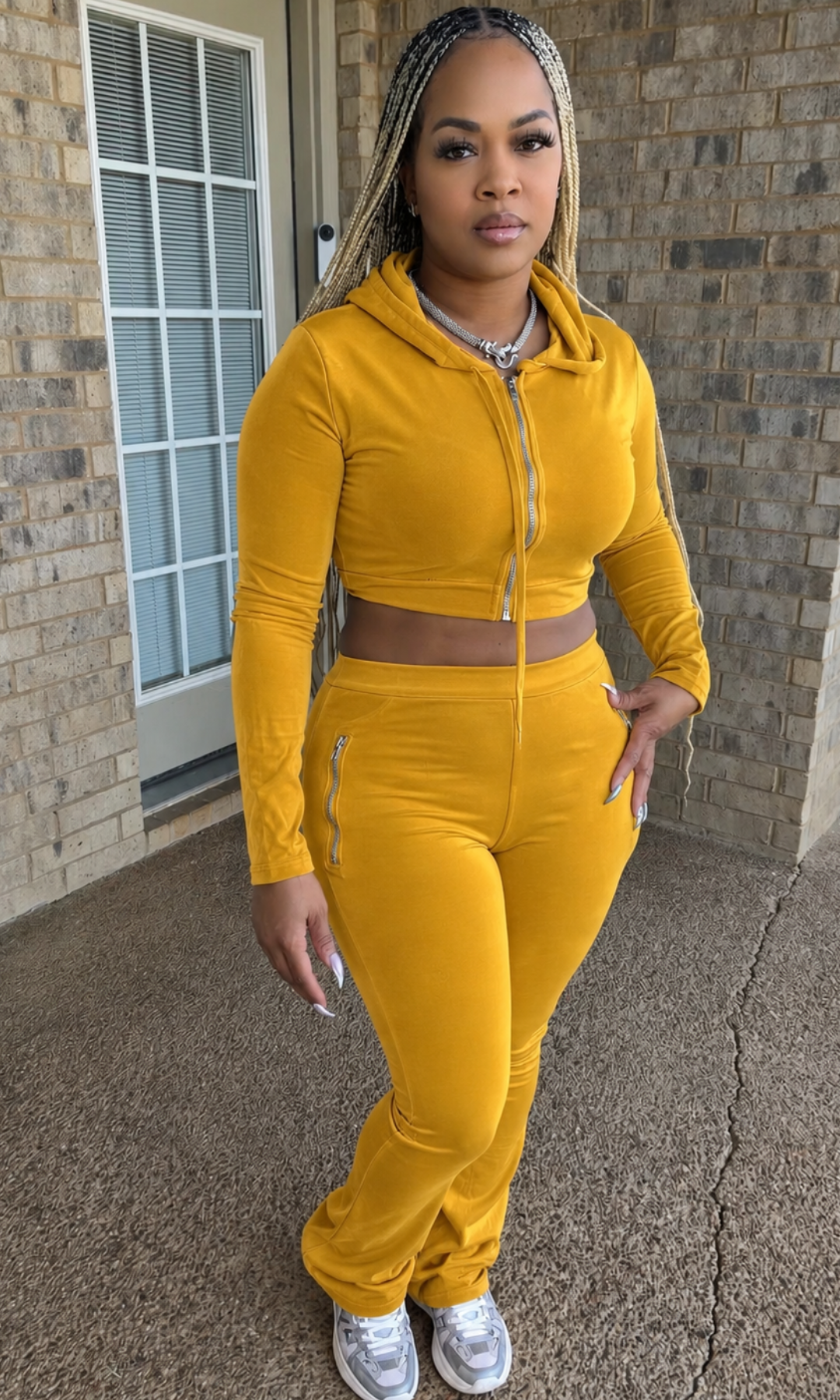 Woman modeling the Honeycomb Hoodie Set in mustard yellow, featuring a cropped zip-up hoodie with drawstrings and matching high-waisted fitted pants with zipper pocket details.
